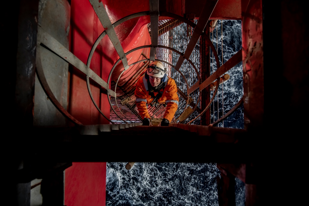 Offshore worker climbing up ladder from sea level. Photo