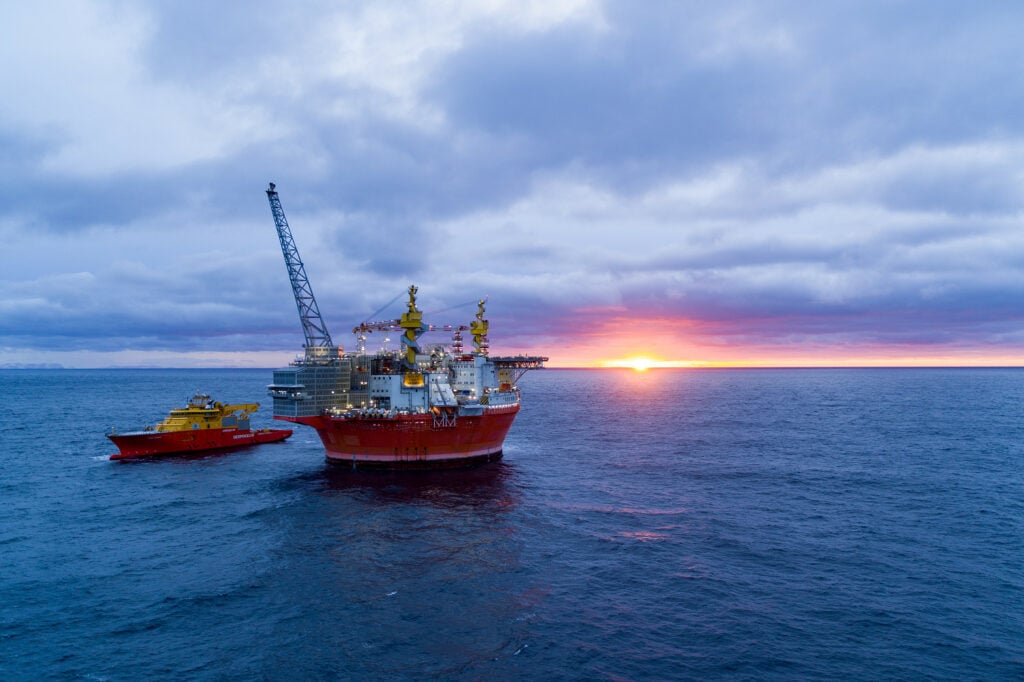 Goliat platform in sunset. Vessel beside the platform. Photo.